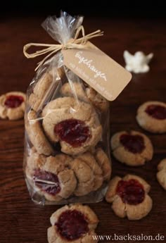 cookies in a bag with jam on the top and small ones around them sitting on a table