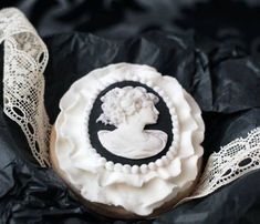 a decorated cookie sitting on top of a black piece of paper with lace around it