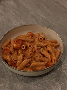 a bowl filled with pasta and sauce on top of a gray countertop next to a knife