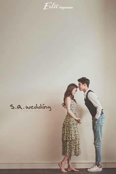 a man and woman standing next to each other in front of a wall with the words s a wedding written on it