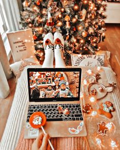 a person sitting in front of a christmas tree with their feet on the laptop keyboard