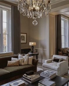 a living room filled with lots of furniture and a chandelier hanging from the ceiling