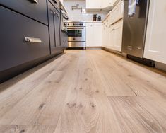 an empty kitchen with white cabinets and wood flooring on the counter top, as well as stainless steel appliances