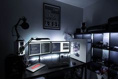 a computer desk with multiple monitors and keyboards on it in a dark room, lit by lights