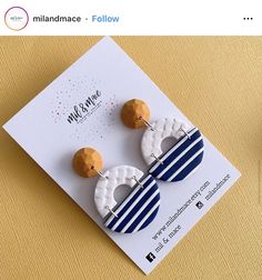 a pair of wooden earrings on top of a white and blue card with the words millinance follow