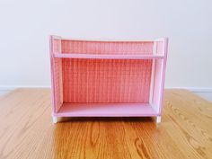 a pink shelf sitting on top of a wooden floor