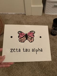 a person holding up a sign that says zeta tau alpha with a butterfly on it