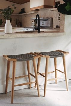 two wooden stools sitting next to each other in front of a kitchen counter top