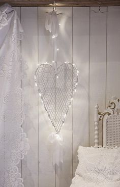 a white bed sitting under a heart shaped light