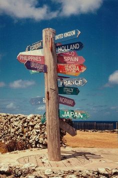 a wooden pole with many different colored signs on it's side near the ocean