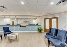 an empty waiting room with blue chairs in it