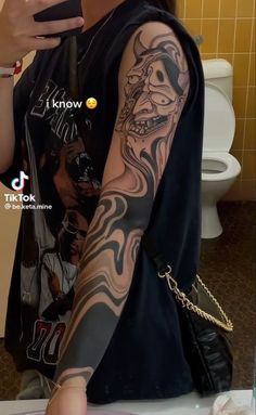 a woman with tattoos on her arm taking a selfie in a bathroom mirror while holding a cell phone