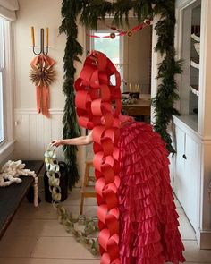 a woman is decorating a house with red paper