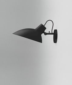 a black lamp on a white wall in the middle of an empty room with grey walls