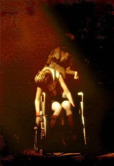 a woman sitting on top of a chair in a dark room with her legs crossed