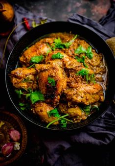 chicken curry with cilantro and parsley in a black bowl on a table