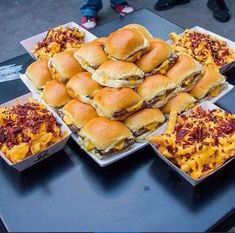 several trays filled with sandwiches and macaroni cheese on top of a table