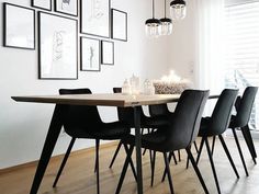 a dining room table with black chairs and pictures on the wall