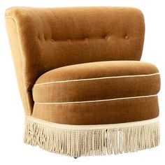 an upholstered chair with fringe trim around the legs