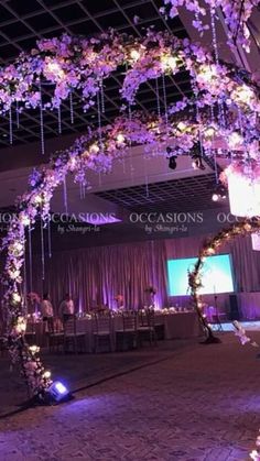 an indoor event with purple flowers on the ceiling