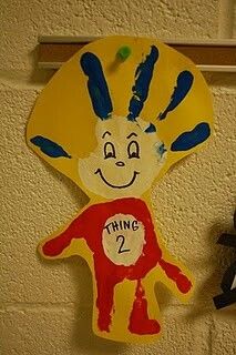 a child's handprinted paper doll hanging on the wall