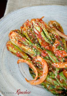 asparagus with tomato sauce and sesame seeds in a white bowl on a table