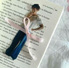 a book with a pink ribbon on top of it next to an image of a person