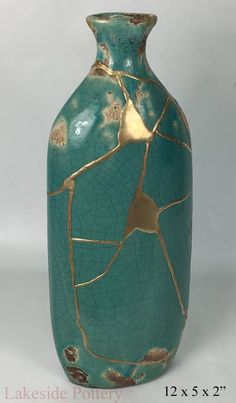 a green vase with gold leaf designs on it