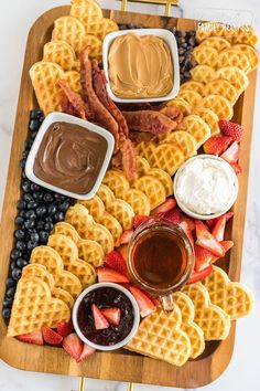 waffles, fruit and dip are on a wooden platter with other foods