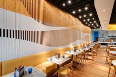 an empty restaurant with yellow booths and wooden wall dividers on either side of the tables