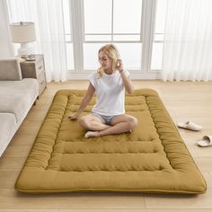 a woman sitting on top of a mat in the middle of a living room area