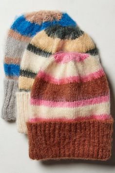 two knitted hats sitting next to each other on a white surface, one with multicolored stripes