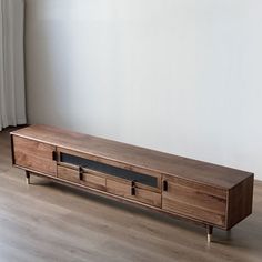 a wooden entertainment center sitting on top of a hard wood floor next to a window