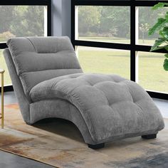 a gray chaise lounger sitting on top of a rug next to a window