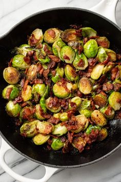 brussel sprouts with bacon in a skillet on a marble counter