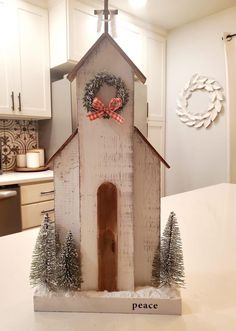 a small wooden church with wreaths on the front and side, sitting on a kitchen counter