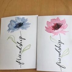 an open book with two watercolor flowers on the pages, one is pink and blue