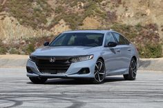 a silver honda accord is parked in front of a mountain side with no one around it