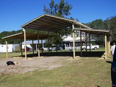 a car parked under a covered area in the middle of a field next to a building