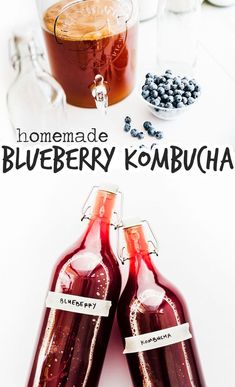 two bottles of blueberry kombucha sitting on a table next to some berries