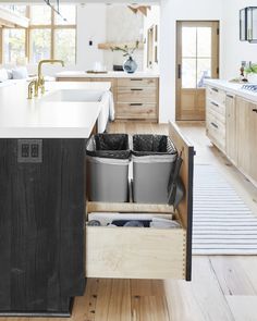 an open kitchen drawer with two trash cans in it