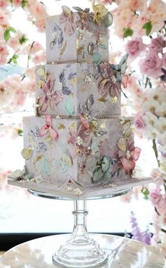 a three tiered cake sitting on top of a white table next to pink flowers