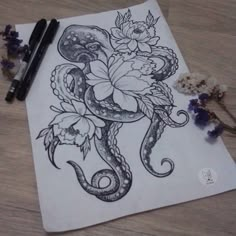 a drawing of an octopus with flowers on it next to some ink pens and paper