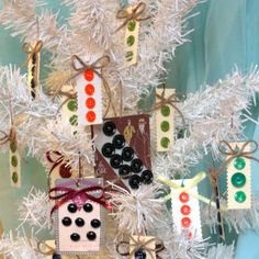 a white christmas tree decorated with buttons and ribbon, ribbons on the top is an ornament that has been made to look like a snowman