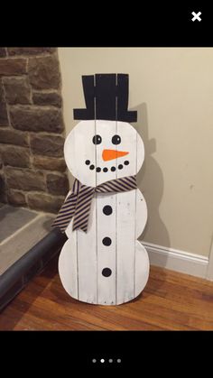 a snowman made out of wood sitting on top of a wooden floor