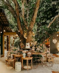 an outdoor dining area with tables and chairs under a large tree in the middle of it