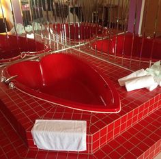 a red bath tub sitting next to two mirrors