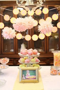 a table topped with lots of cakes and cupcakes next to a chandelier