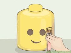 a person is painting a yellow jar with a smiley face on the front and side