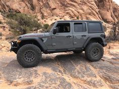 a gray jeep parked on top of a rocky hill